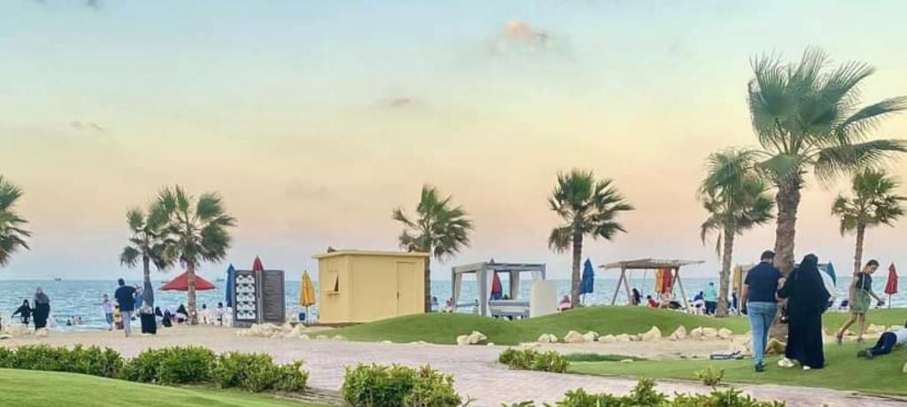 um grupo de pessoas caminhando ao longo de uma praia com palmeiras em Porto Said Resort Rentals em Port Said