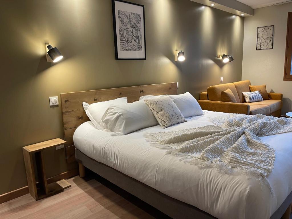 een slaapkamer met een groot bed en een bank bij Cit'Hôtel le Welcome in Moutiers