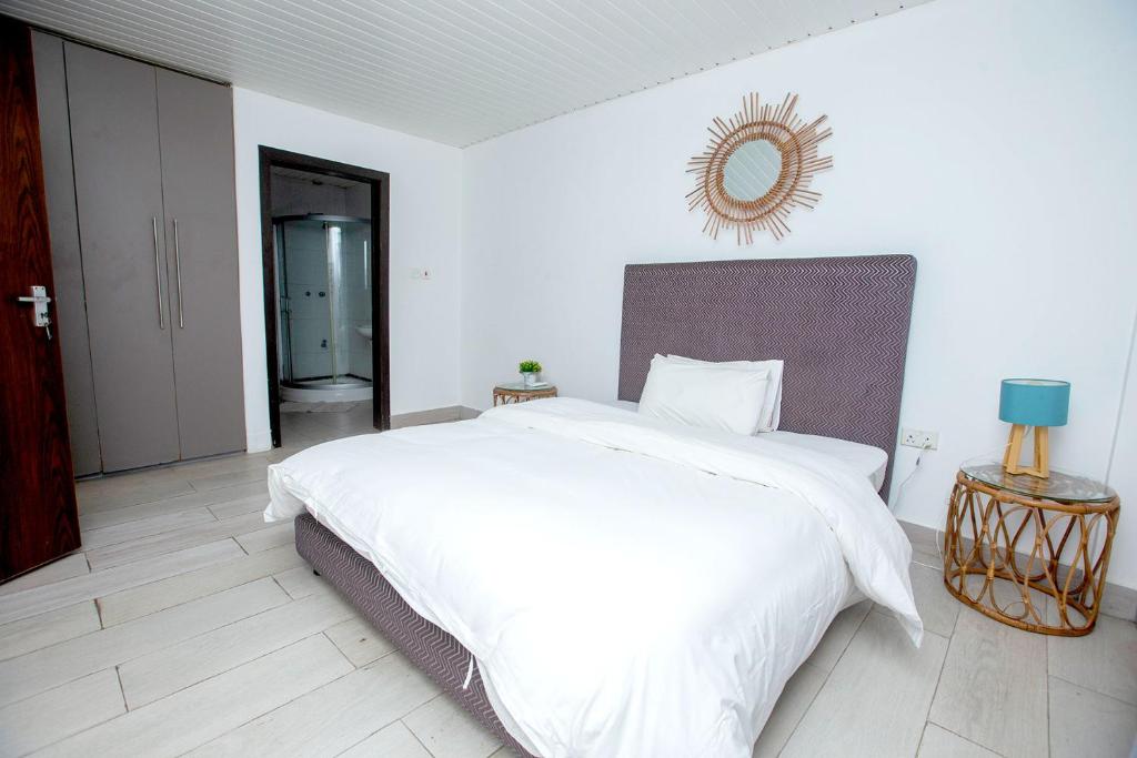 a bedroom with a large white bed and a mirror at South La Apartments in Accra