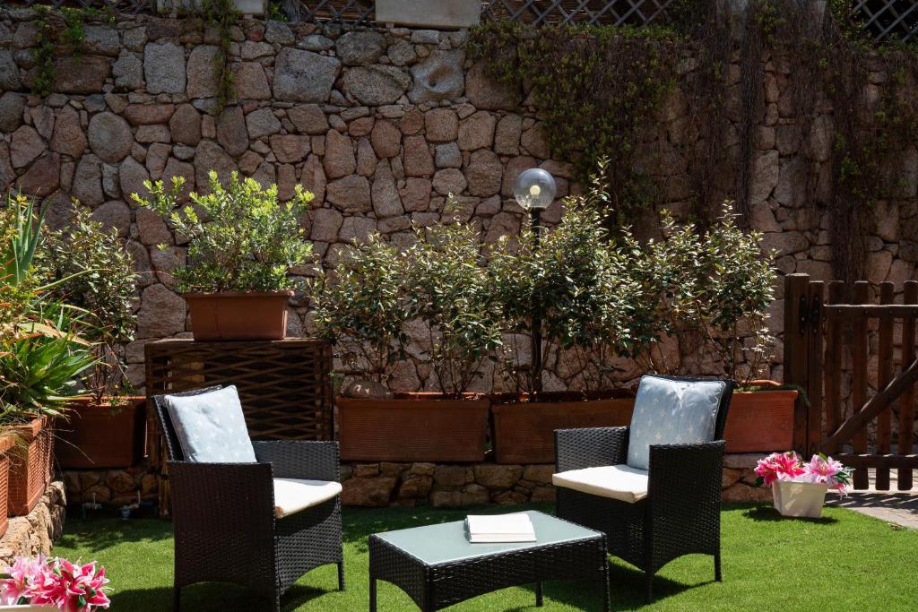 un patio con sedie, tavolo e parete in pietra di Harry's House by Wonderful Italy a Porto Rotondo