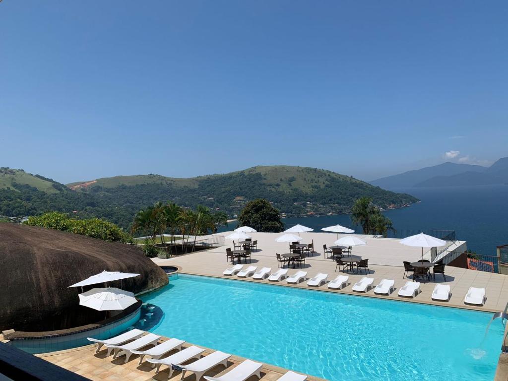 een zwembad met stoelen en parasols op een resort bij Portogalo Suite Hotel in Angra dos Reis