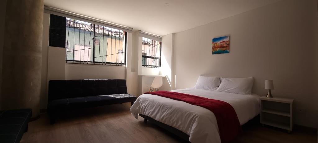 a bedroom with a bed and a couch and two windows at New Comfortable Apartments in La Candelaria, Bogotá in Bogotá