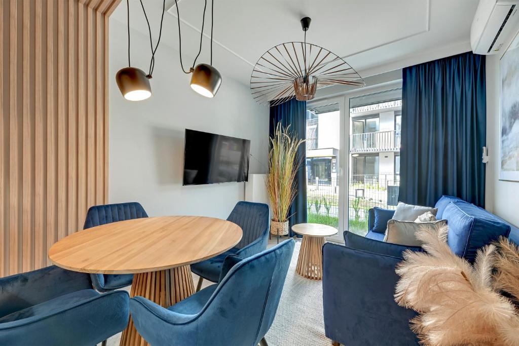 a living room with a wooden table and blue chairs at GRANO FLATS Sobieszewo - Baltic Line in Gdańsk