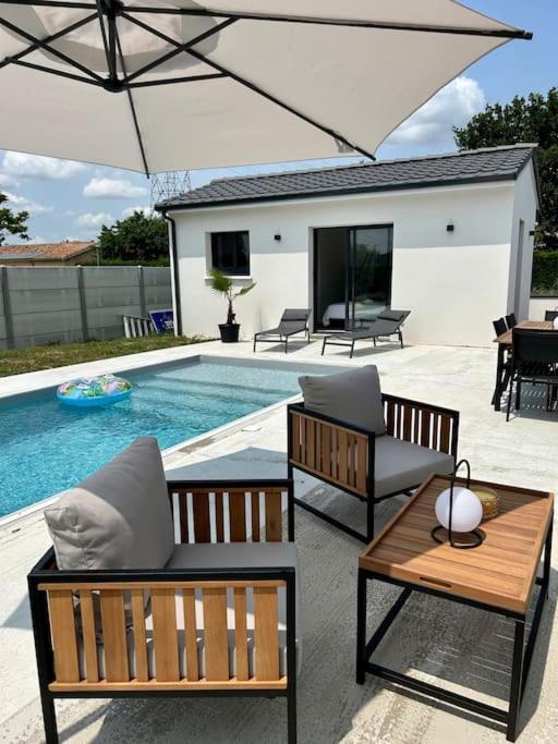uma piscina com duas cadeiras, uma mesa e um guarda-sol em Studio Isana - avec piscine em Ambarès-et-Lagrave