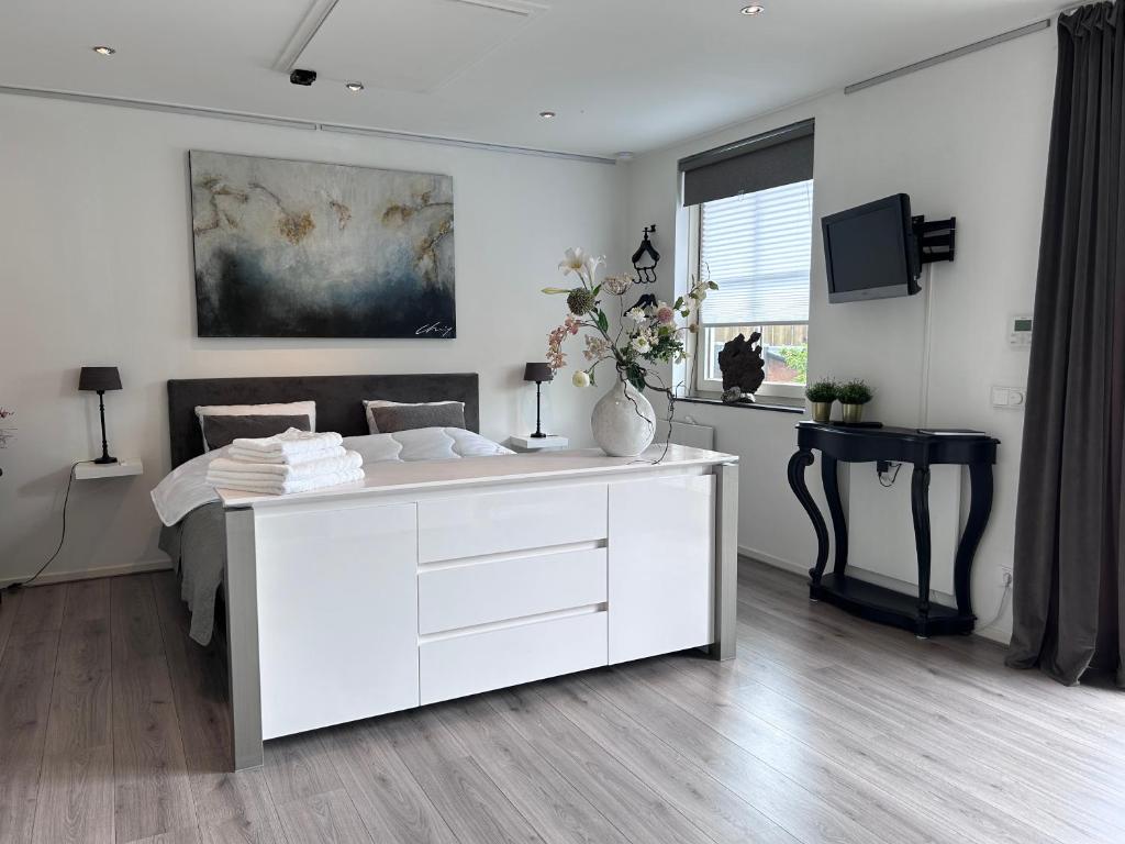 een witte slaapkamer met een bed en een televisie bij De Kamperveste in Kampen
