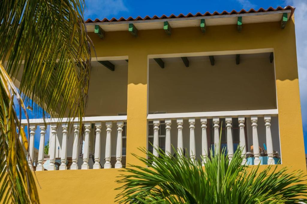un bâtiment jaune avec une clôture blanche et des palmiers dans l'établissement 28B Casa Kokolishi, à Kralendijk