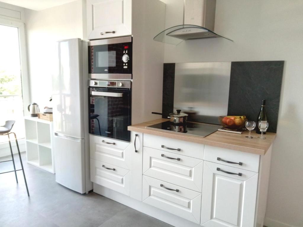 a kitchen with white cabinets and a refrigerator at Appartement lumineux pour 6 in Hérouville-Saint-Clair