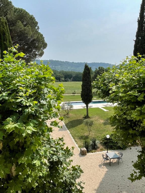 a park with a bench and a tree and a pool at La Pavoyère in Mormoiron