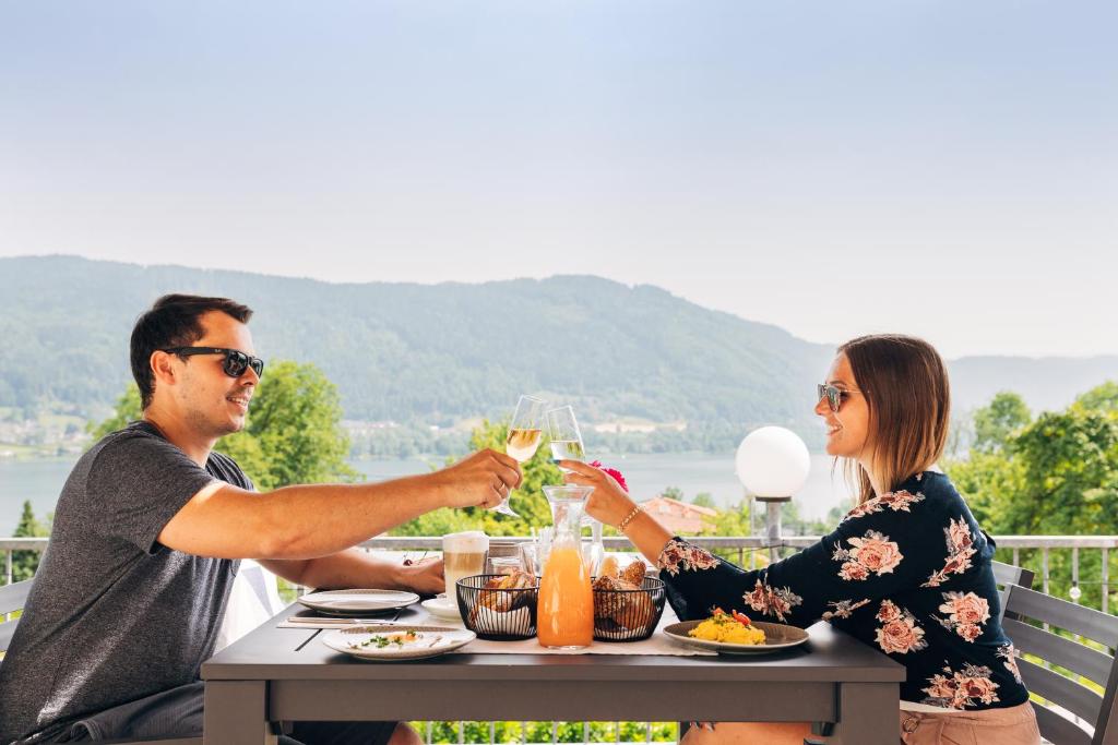 Ein Mann und eine Frau sitzen am Tisch und trinken Wein. in der Unterkunft Gasthof Nindler in Steindorf am Ossiacher See