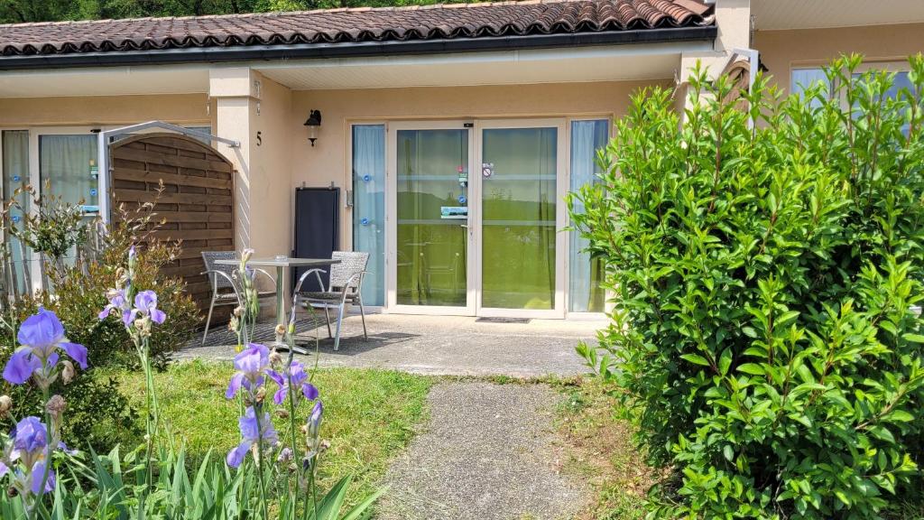 a house with a glass door with a table and chairs at Hotel La Peyrade in Cajarc