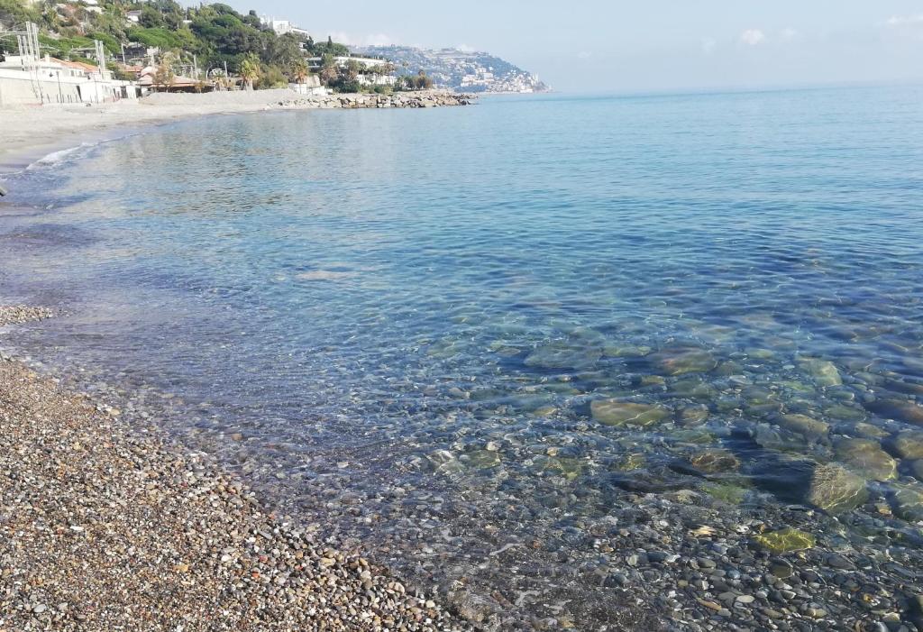 a beach with clear blue water and a rocky shore at Casa Ambra mare in Bordighera