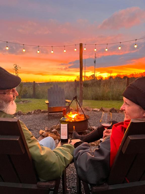 two people sitting around a fire pit with wine glasses at Pousada Costaneira in Cambará