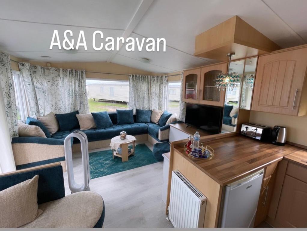 uma cozinha e sala de estar com um sofá e uma mesa em A&A Caravan Holidays em Leysdown-on-Sea