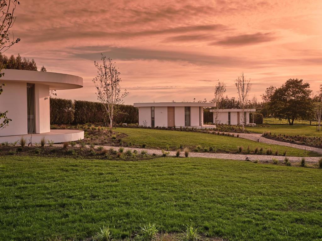 a row of white buildings in a grassy field at Retiro Costiña Wellness&villas in Santa Comba