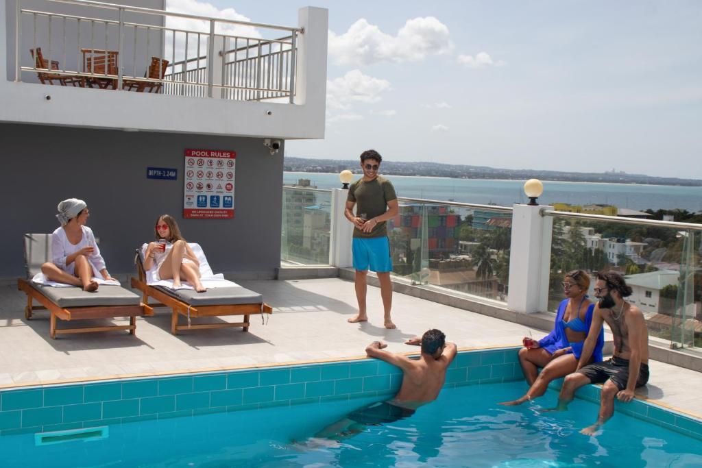 grupa ludzi siedzących wokół basenu w obiekcie Tanzanite Serviced Apartment - TSA Masaki w mieście Dar es Salaam