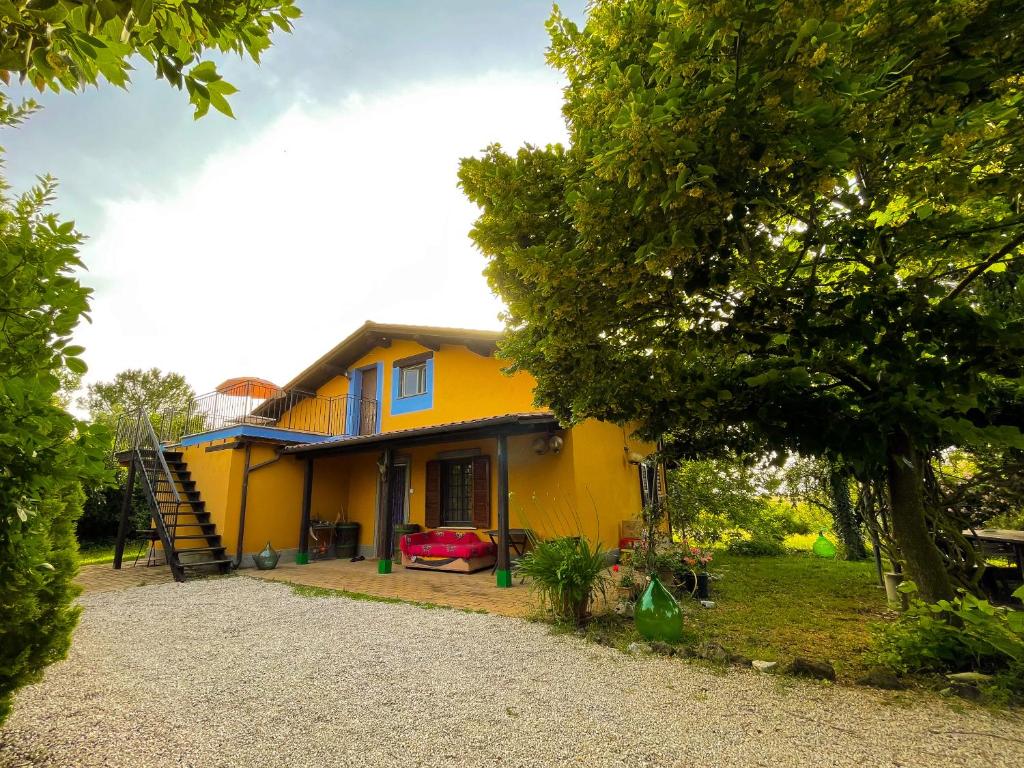 a yellow house with a tree in front of it at Country House tra lago e mare a Sud di Roma in Campoleone