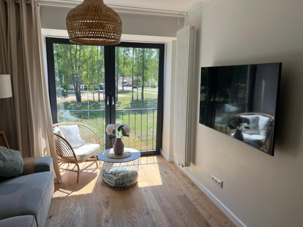 a living room with a couch and a large window at Albatross Beach Apartment - SPA, Sea and Forest in Ķesterciems