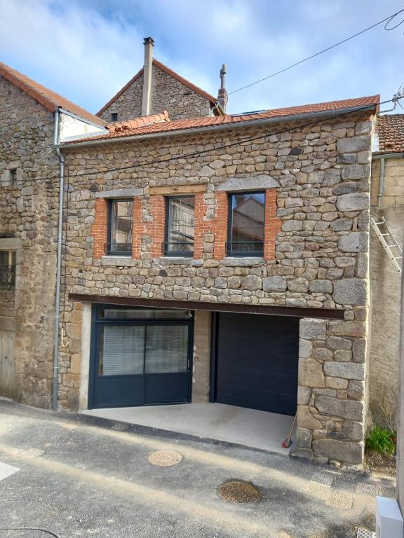une maison en pierre avec deux portes de garage dans l'établissement La Remise de SoSo, à Chambon-le-Château