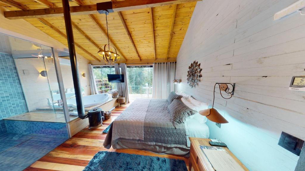 a bedroom with a bed and a tub in a room at Cisne Negro Villarejo in Urubici