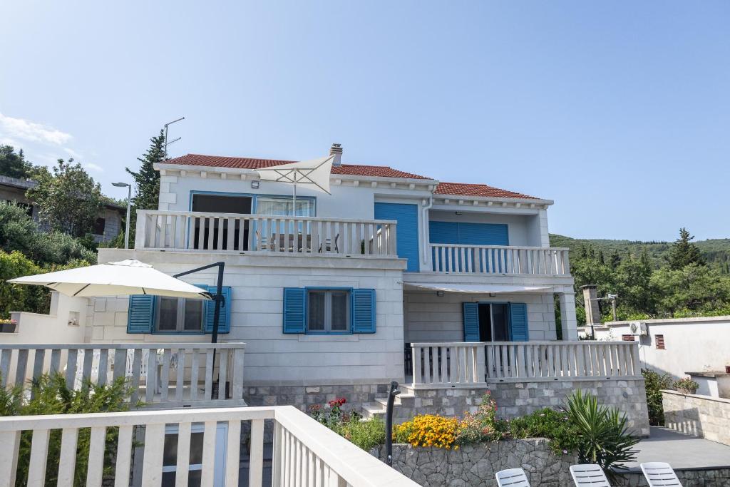 ein Haus mit blauen Fensterläden und einem Balkon in der Unterkunft Apartments Seafront in Pupnat