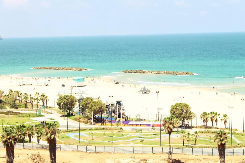 - une plage avec des palmiers et des personnes sur la plage dans l'établissement Best Beach View, Gym, Massage Chair, Low Fee For Off-Site Indoor Pool, Spa & Breakfast נוף ים מאלף, כיסא מסאז, חדר כושר, אפשרות לארוחת בוקר כשר, בריכה מקורה, וספא בתשלום ממש מוזל, à Ashkelon