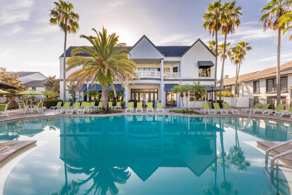 a swimming pool in front of a house with palm trees at Legacy Vacation Resorts Kissimmee & Orlando - Near Disney in Kissimmee