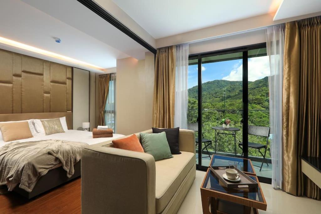um quarto com uma cama, um sofá e uma varanda em Apartment walking to Surin Beach by Capital Pro em Phuket