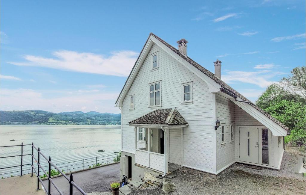 a white house next to a body of water at Cozy Home In ystese With House Sea View in Øystese