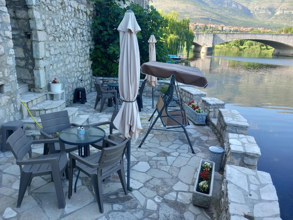 einen Tisch und Stühle mit einem Regenschirm neben einem Fluss in der Unterkunft Castello in Trebinje