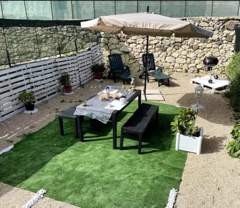een tafel met een paraplu en twee stoelen en een tafel en sidx sidx sidx sidx bij Casa Osiride con giardino privato e barbecue in Nulvi