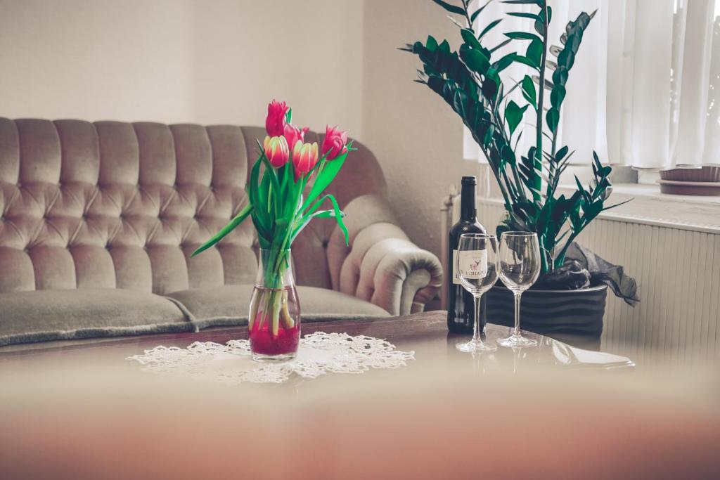 una mesa con un jarrón de flores y dos copas de vino en Hotel Komfort Inn - Dwór Hubertus, en Piekary Śląskie