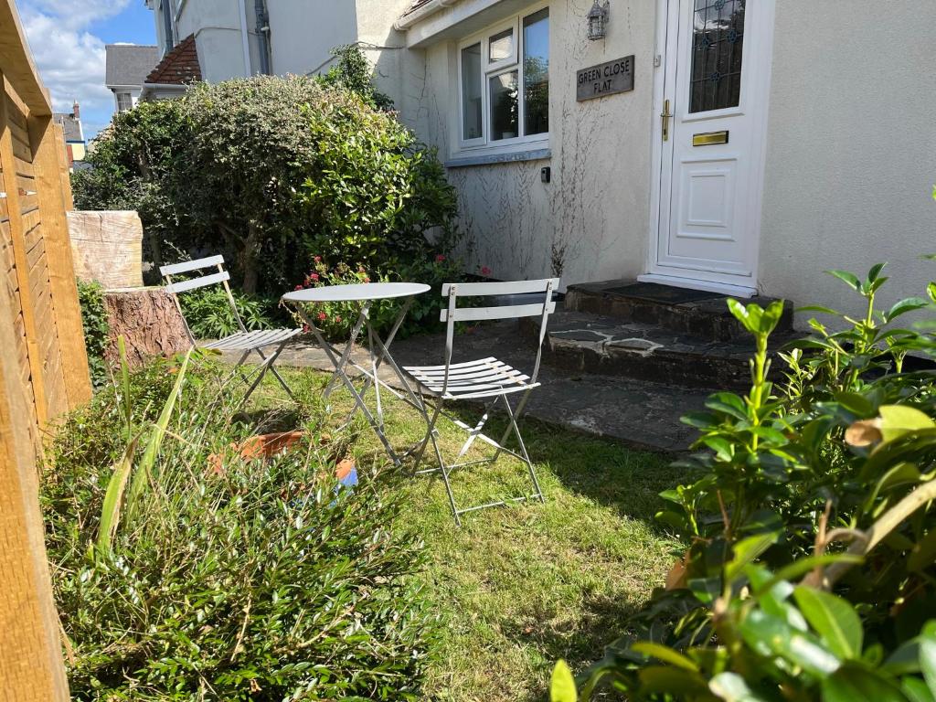 two chairs and a table in front of a house at Spacious one bed apartment in a quiet leafy close. in Barnstaple