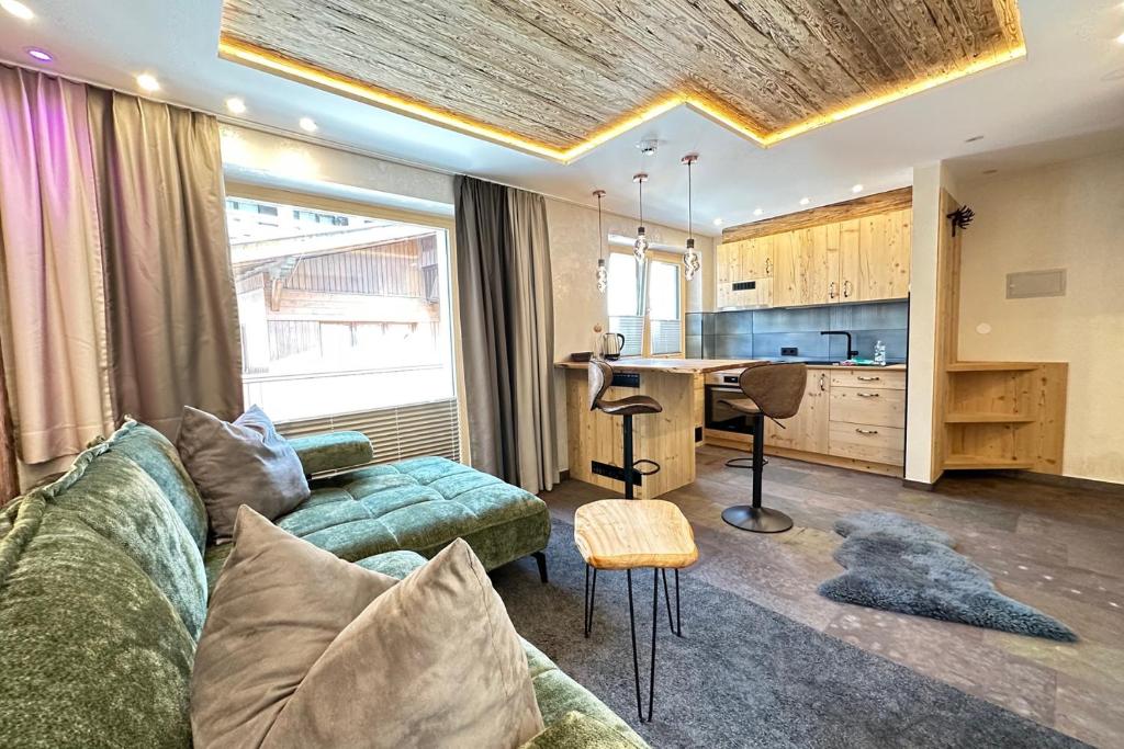 a living room with a couch and a table and a kitchen at Quality Hosts Arlberg - ALPtyrol Appartements in Sankt Anton am Arlberg