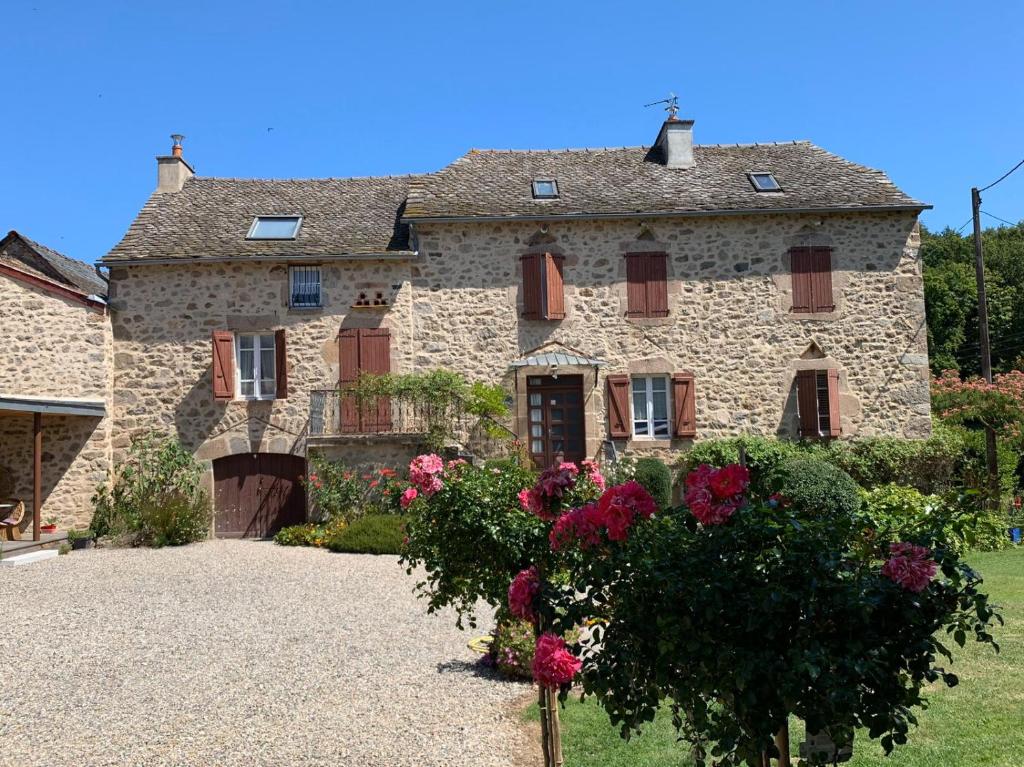 una grande casa in pietra con dei fiori di fronte di La Maison Rouziès a La Bastide-lʼÉvêque