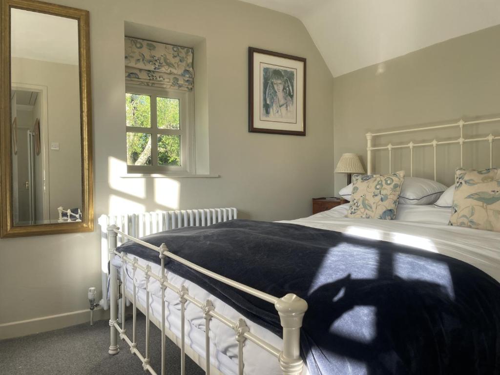a bedroom with a white bed and a window at The Old Coach House in Redlynch