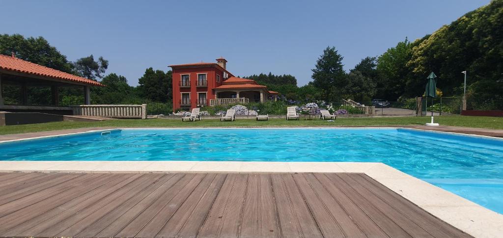 a swimming pool with a wooden deck and a house at Villam Natura & Spa in Vila Nova de Famalicão