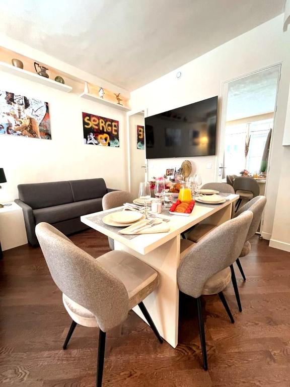 une table à manger et des chaises dans un salon dans l'établissement Appartement Villiers, à Paris