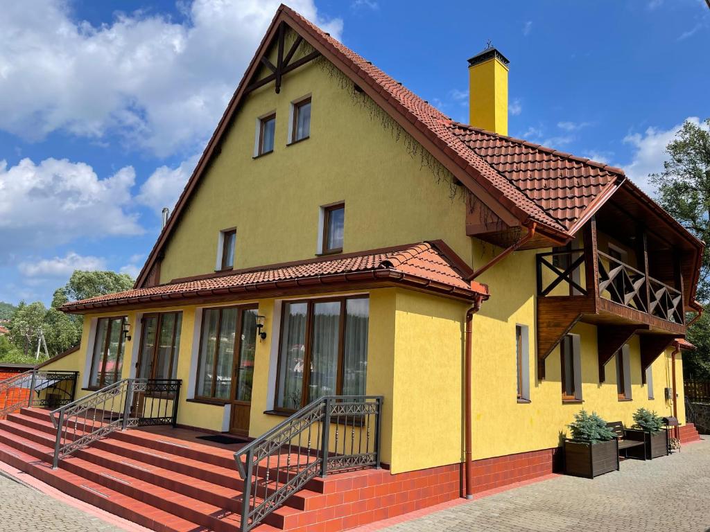 una casa amarilla con porche y techo en TOTEM, en Skhidnytsya