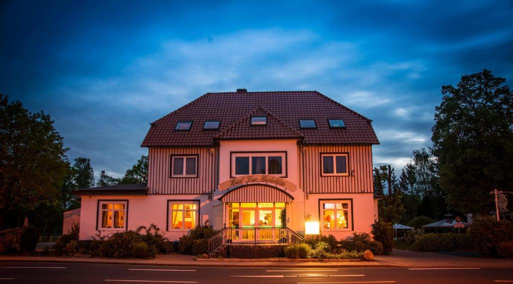 a pink house with a black roof at Hotel zur Heideblüte in Hambühren