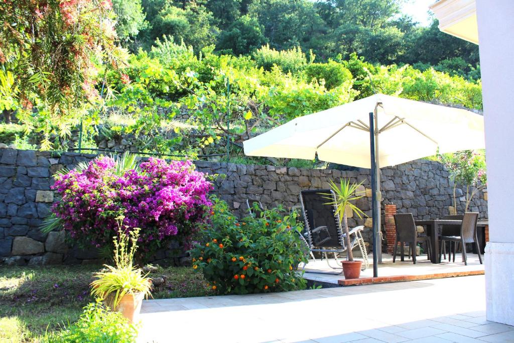 a patio with an umbrella and some flowers at Casa Vacanze A Ravà in Francavilla di Sicilia