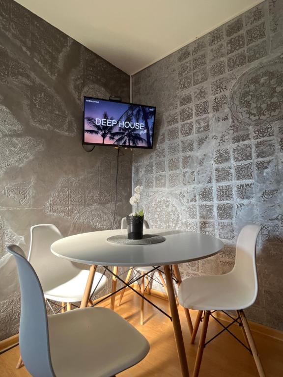 een tafel en stoelen met een tv aan de muur bij Prva Apartment in Novi Pazar