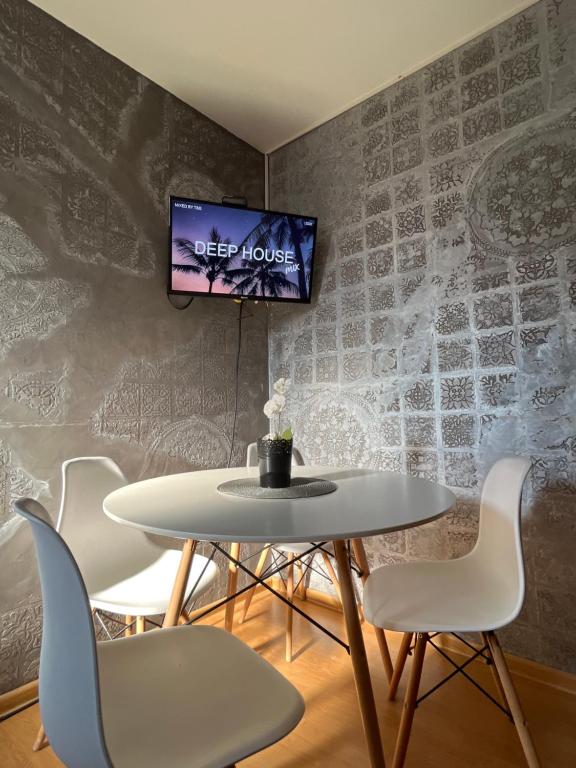 a table and chairs with a tv on a wall at Prva Apartment in Novi Pazar