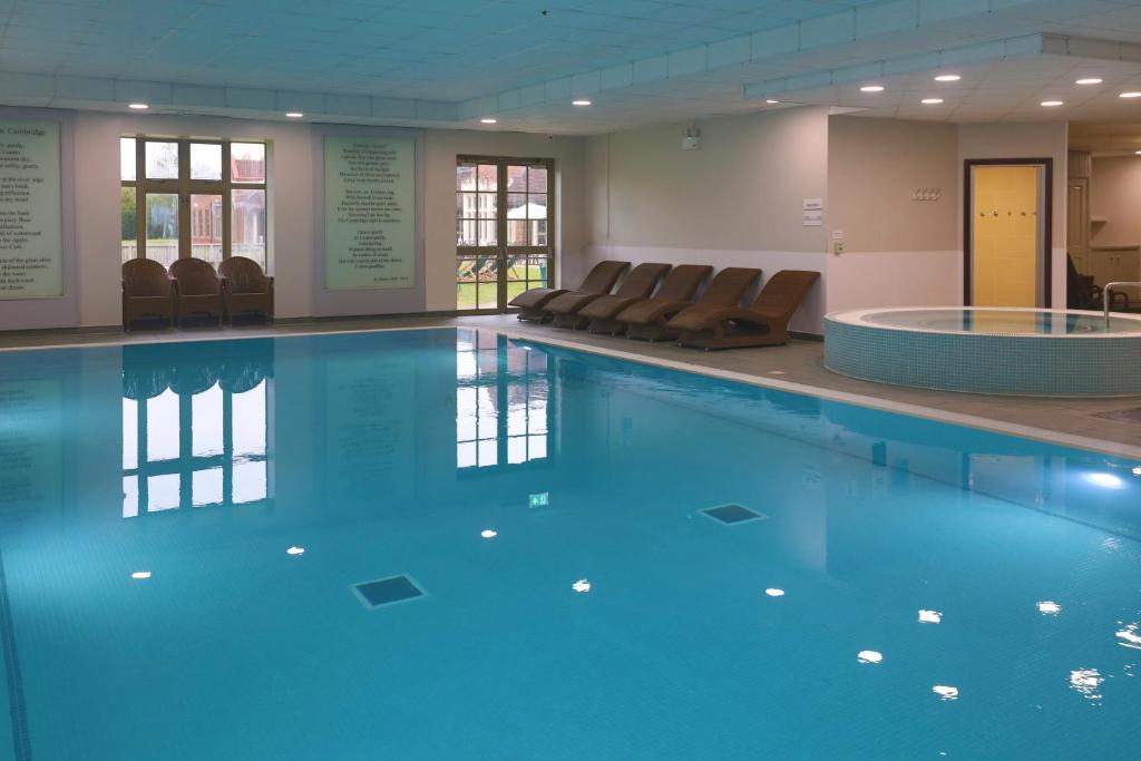 ein großer Pool mit Stühlen in einem Gebäude in der Unterkunft Cambridge Belfry Hotel & Spa in Cambridge
