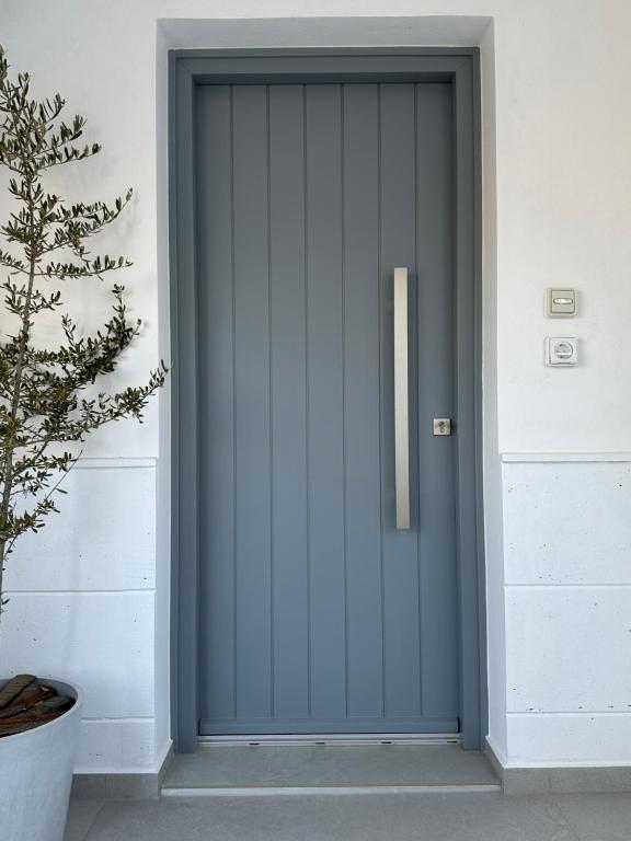 una puerta delantera azul de una casa con una planta en A drop from the sea, en Finikas
