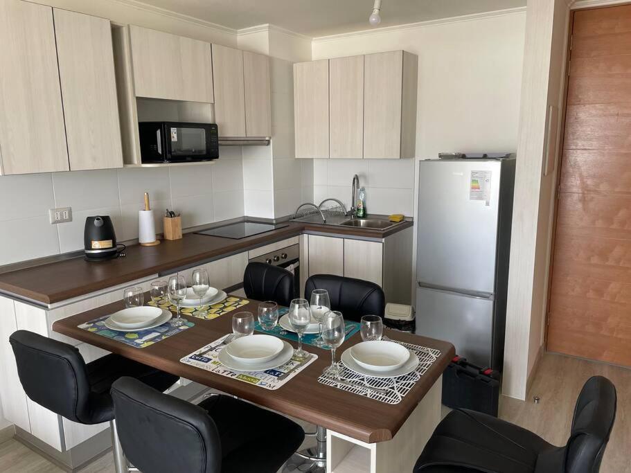 eine Küche mit einem Tisch mit Stühlen und einem Kühlschrank in der Unterkunft Excelente departamento nuevo a pasos de la playa in La Serena