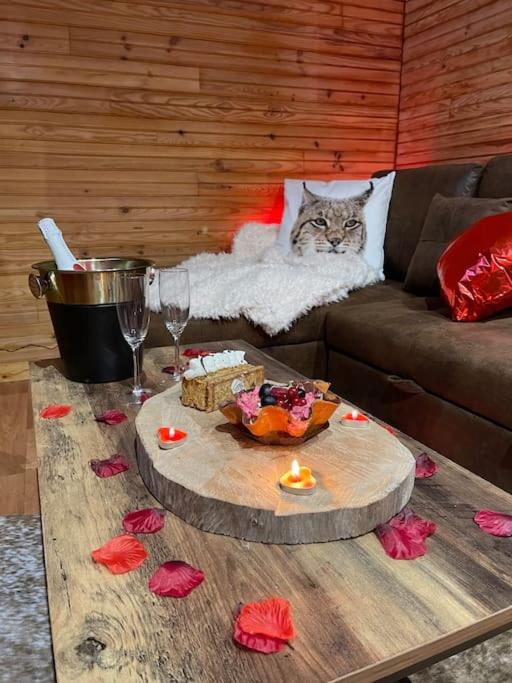 un chat assis sur un canapé à côté d'une table dans l'établissement Romantique chalet avec sauna et jacuzzi extérieur, à Arthon
