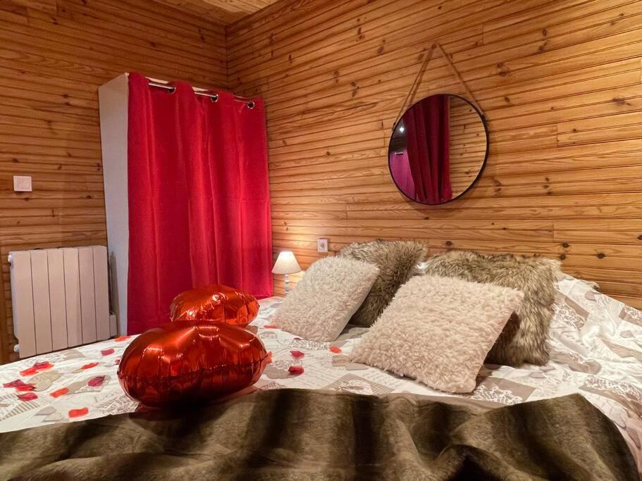 a bedroom with a bed with a red curtain and a mirror at Romantique chalet avec sauna et jacuzzi extérieur in Arthon
