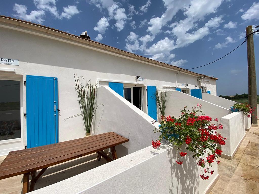 a white house with blue doors and a wooden bench at Auberge des Plaines - Appartements avec terrasse in Arles