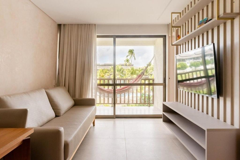 uma sala de estar com um sofá e uma rede de descanso em Apartamento Luxo no Beach Class Resort Muro Alto 3204 em Porto de Galinhas