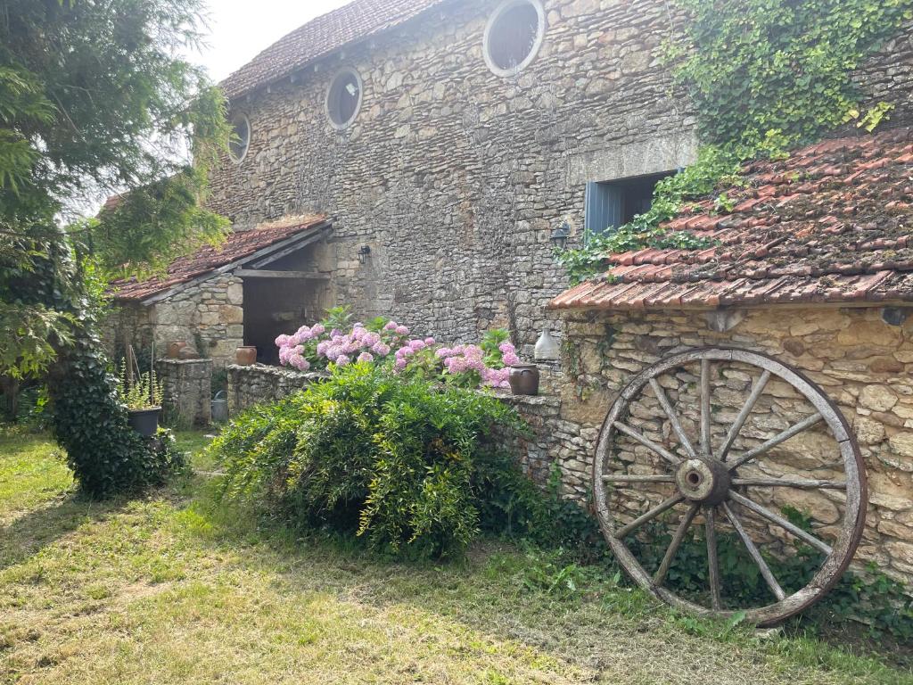 an old stone building with a wheel in front of it at Gîte Le Meynet in Saint-Cyprien